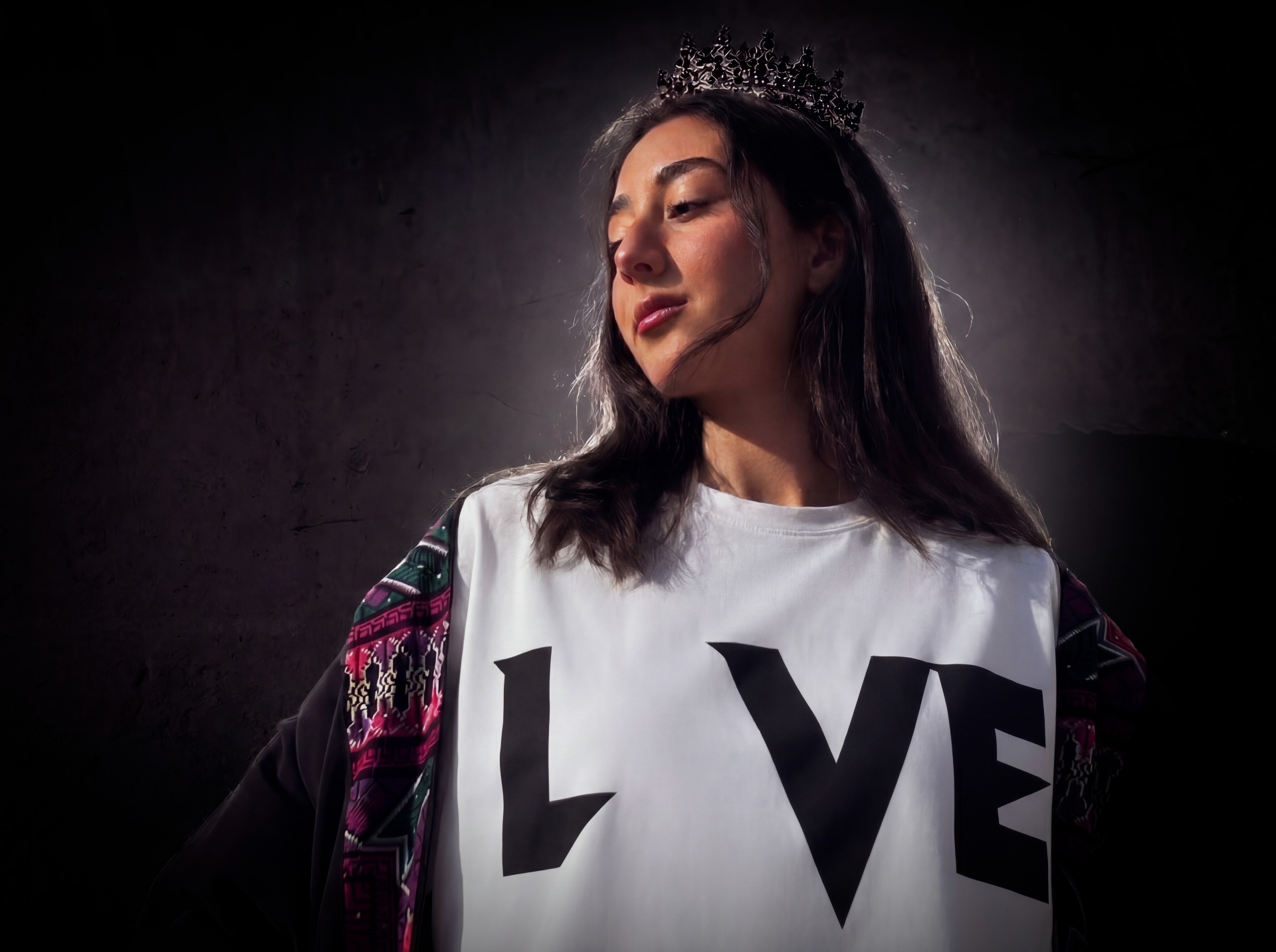 Model wearing a black crown and white Love Des Reves LVE graphic t-shirt in moody cinematic lighting